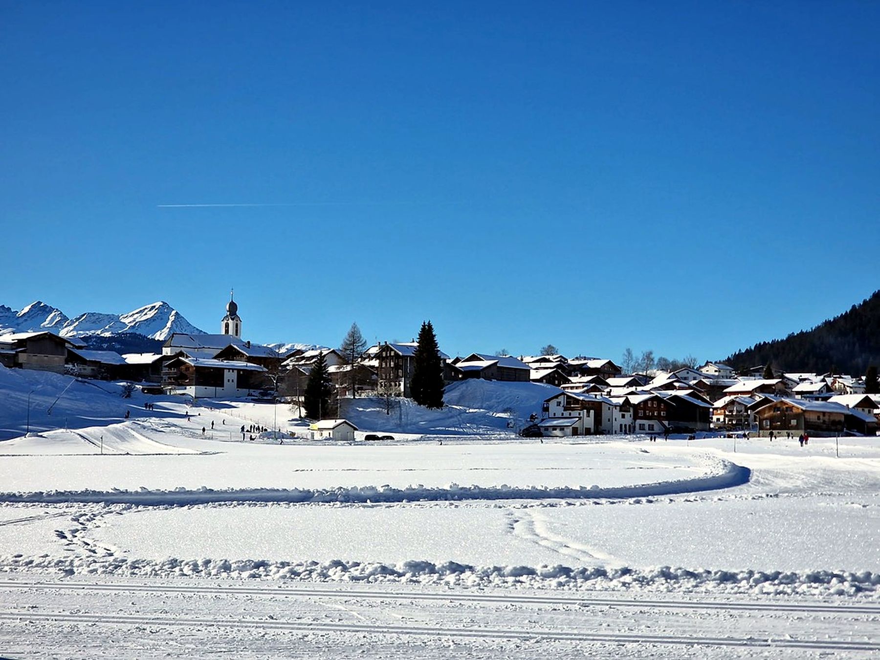 Verschneites Brigels mit Kirche und Langlaufloipe