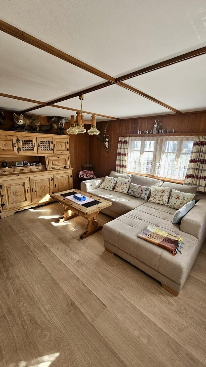 Wohnzimmer mit hellem Ecksofa im Sonnenlicht